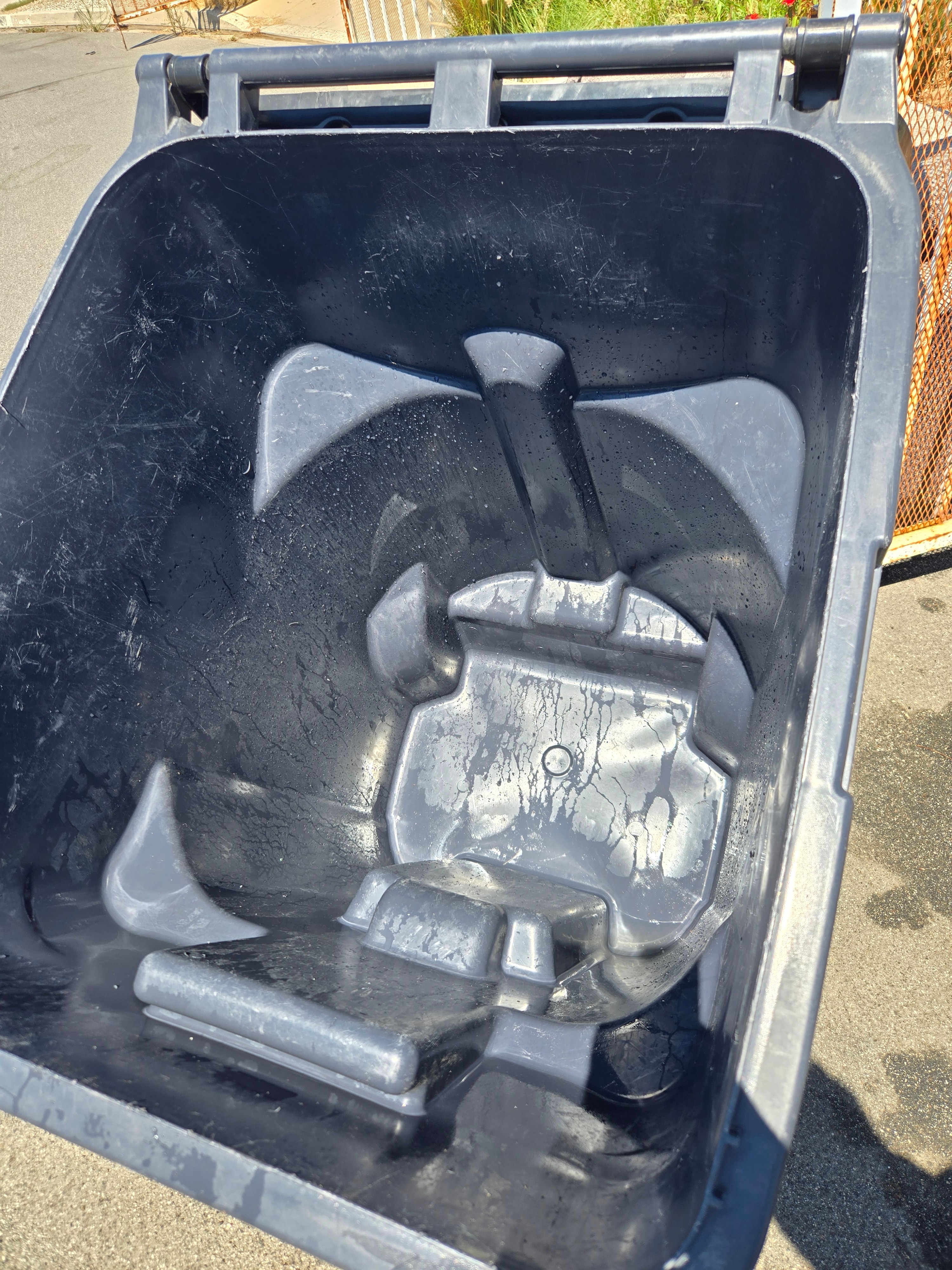 The inside of a trash can washed clean and free of residue after cleaning